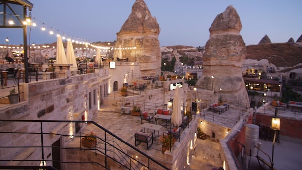 A rooftop terrace with stone walls, outdoor seating, and string lights. - Peruna Cave (Nevsehir)