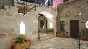 A stone courtyard with wooden planters, a staircase, and a wrought iron railing. - Peruna Cave (Nevsehir)