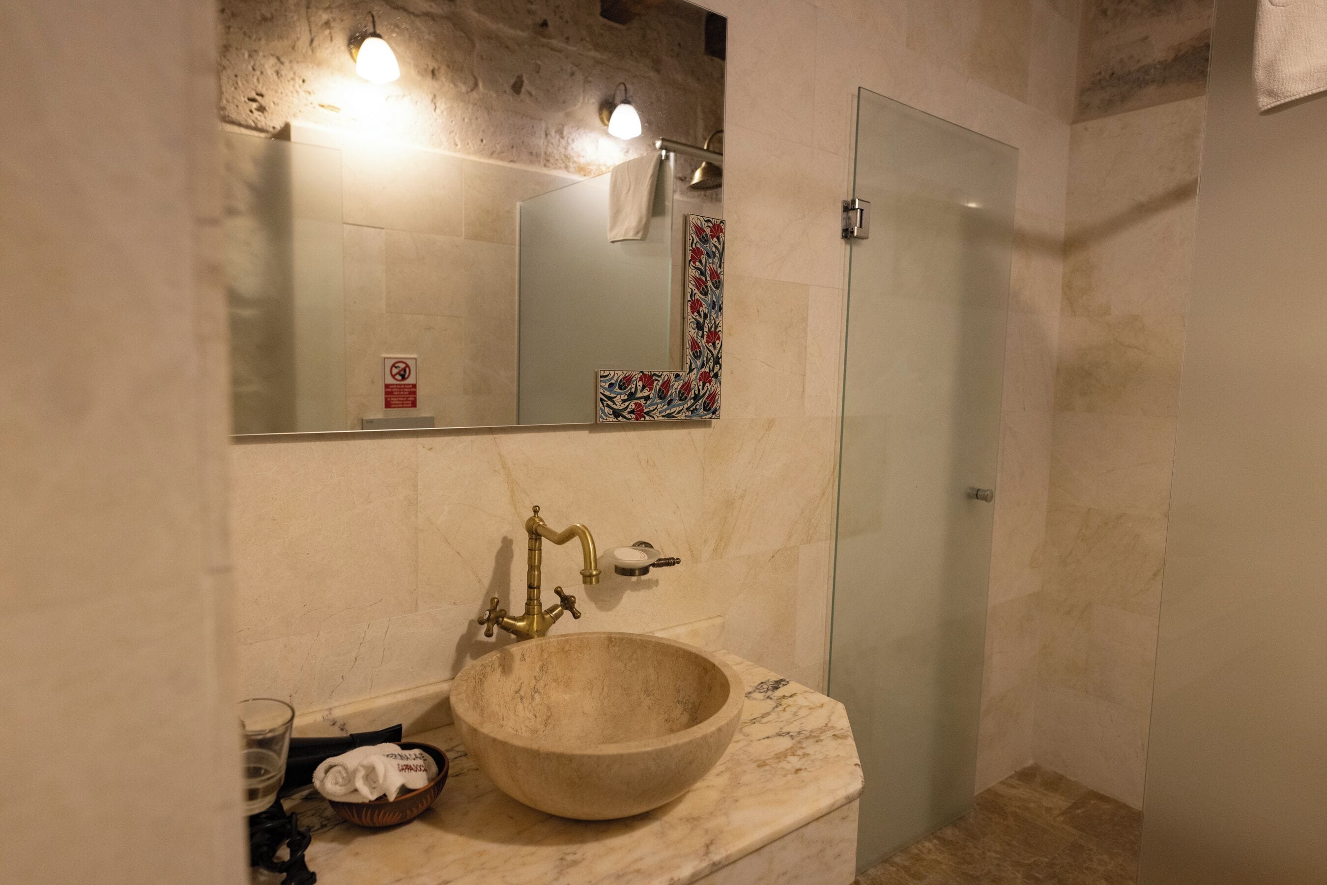 A bathroom with a large marble sink, a mirror, and a glass shower enclosure.