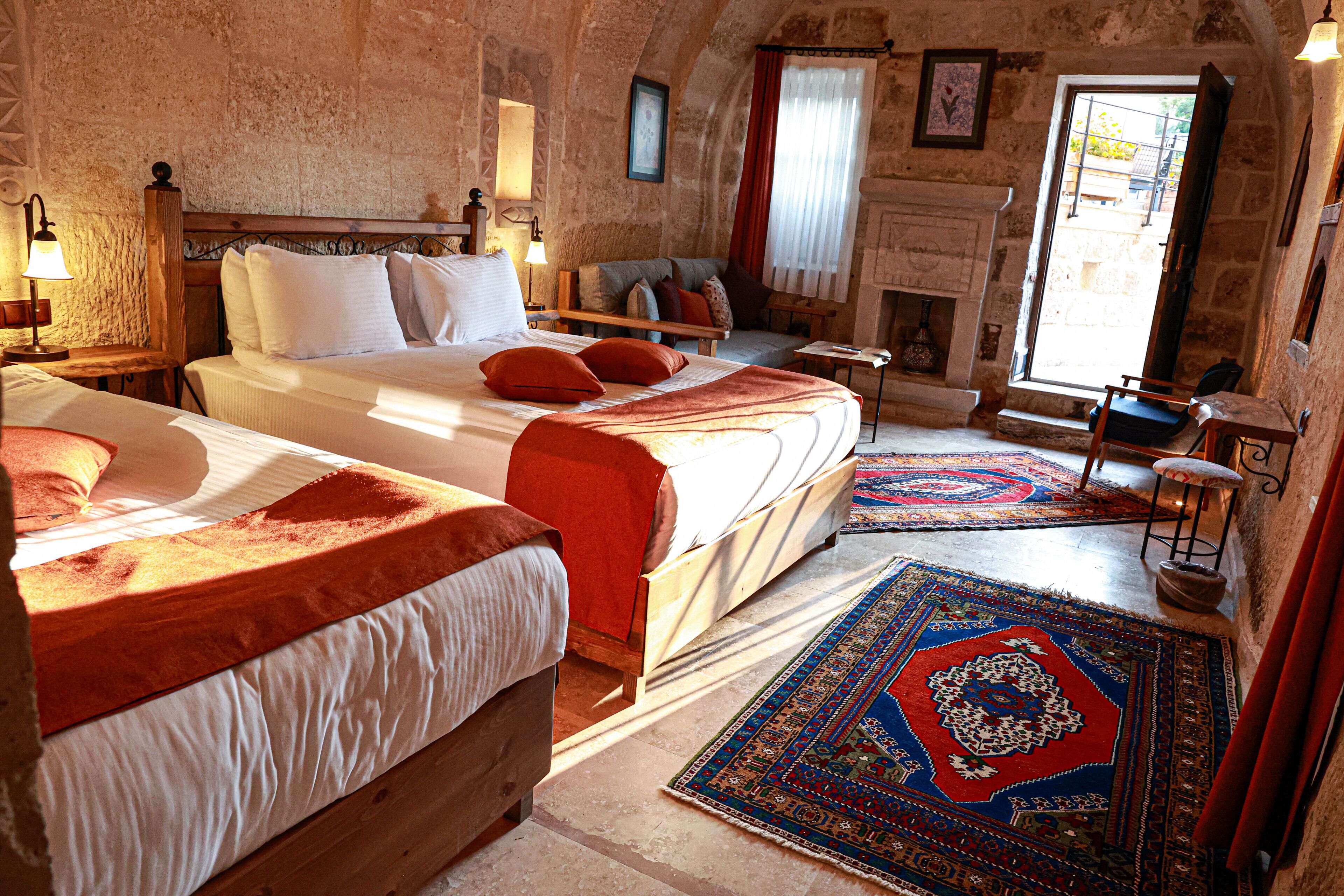 A traditional room with two beds, a fireplace, and a large rug.