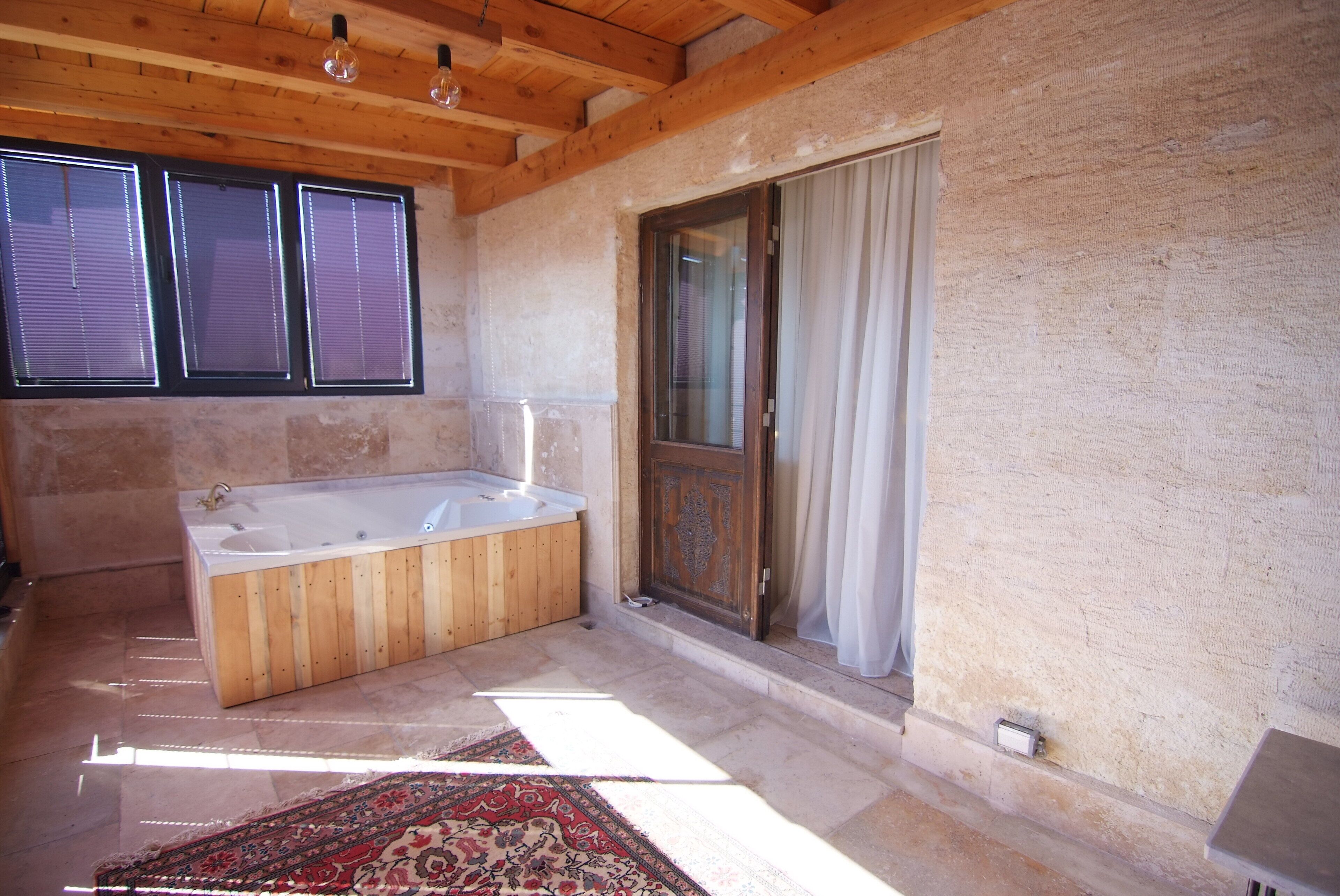 A bathroom with a wooden bathtub, a large window, and a sliding glass door.