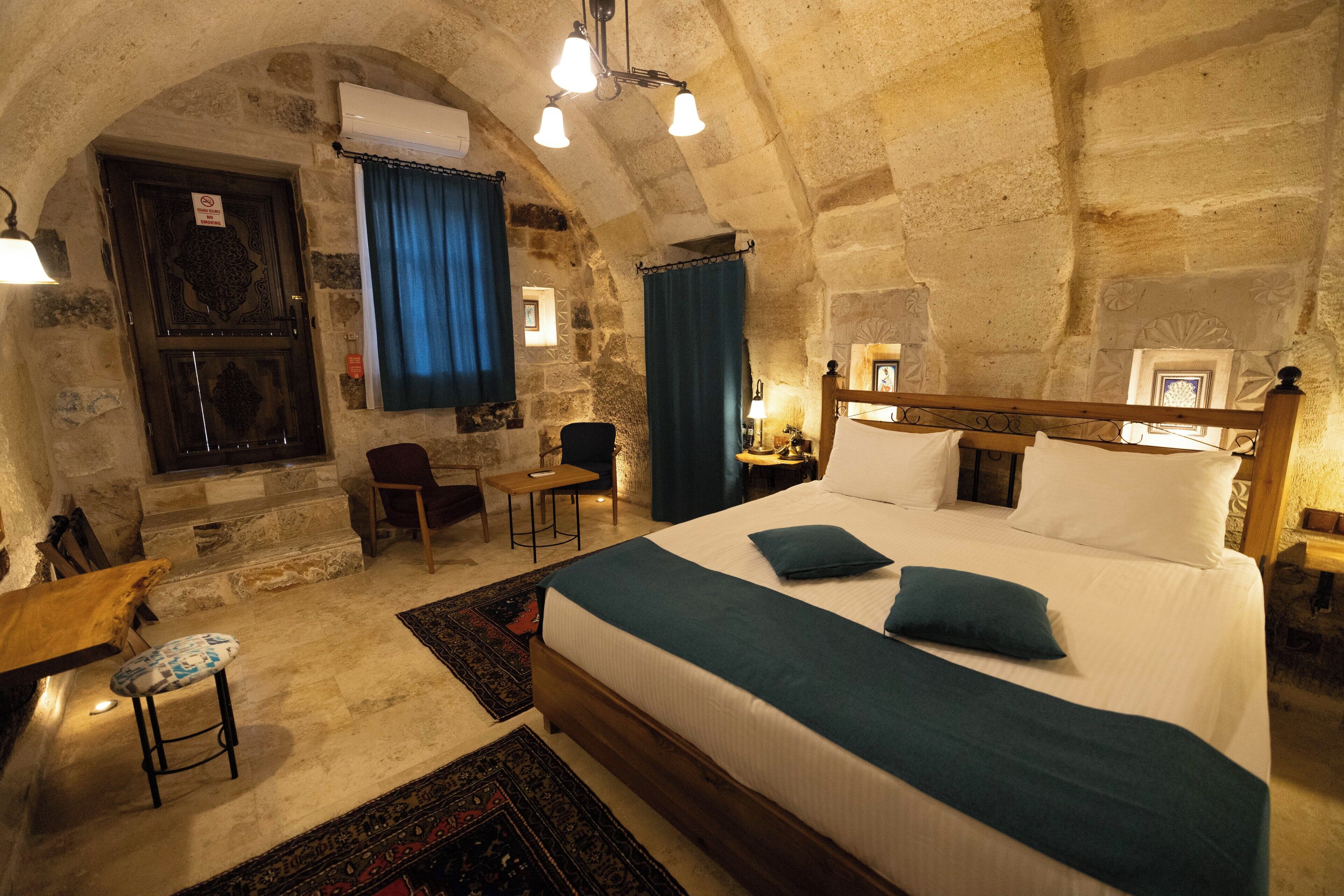 Ein Schlafzimmer mit Stehwänden, einem großen Bett, einem Nachttisch aus Holz, einem Sessel und einem Schreibtisch.