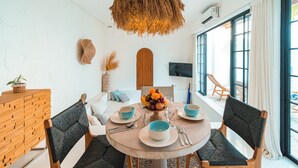 A dining area with a round table, chairs, and a hanging light fixture. - Villa The View (Canggu)
