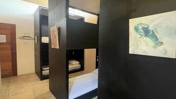 A room with bunk beds, a wooden door, and a painting on the wall.