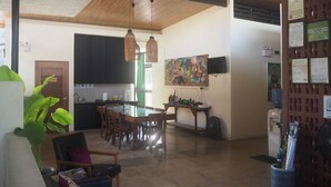 A spacious living area with a dining table, chairs, a kitchen area with cabinets, and a large painting on the wall. - Ceda Guest House by HiveRooms (Santa Fe)