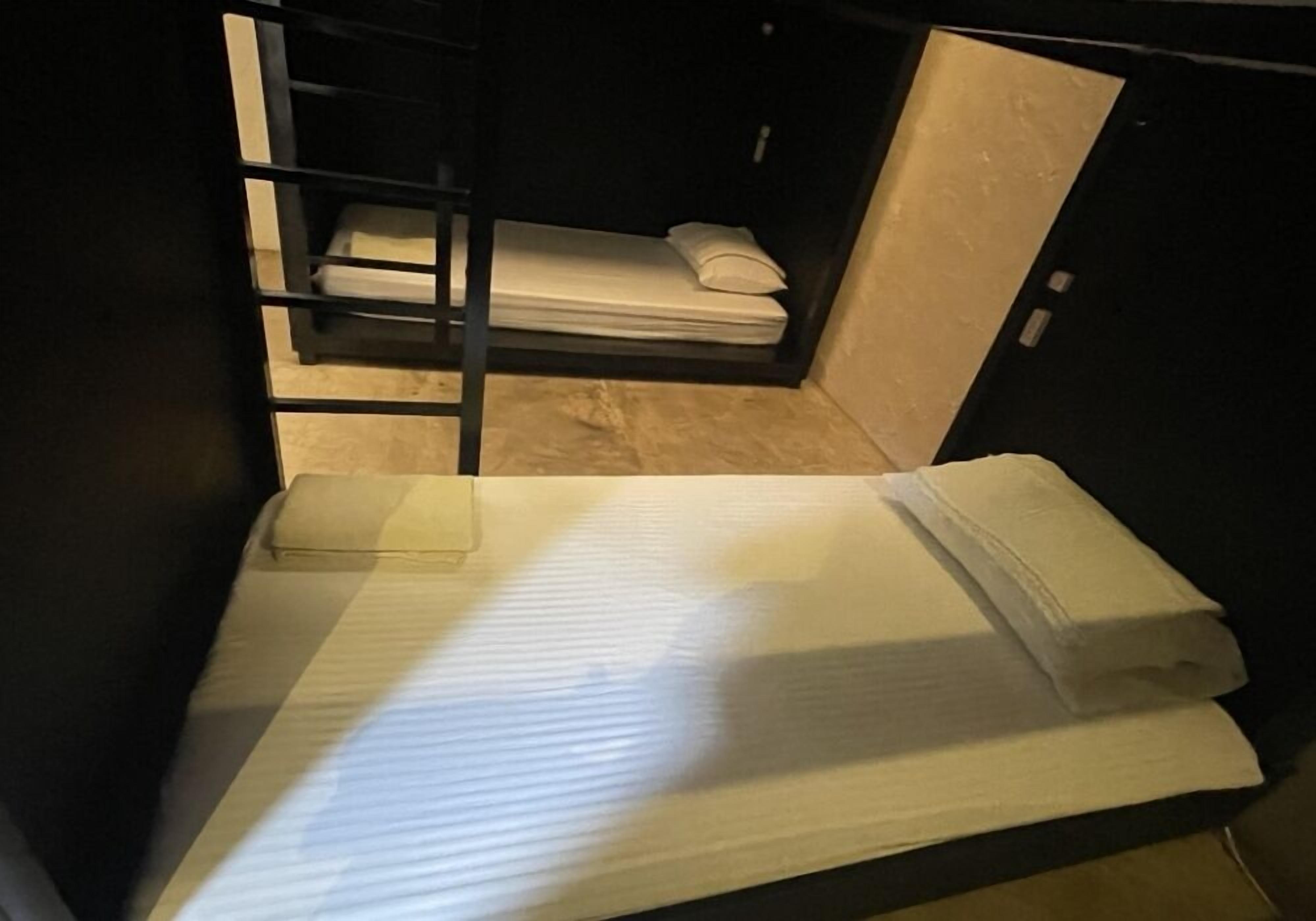Habitación pequeña con literas y una mesita.