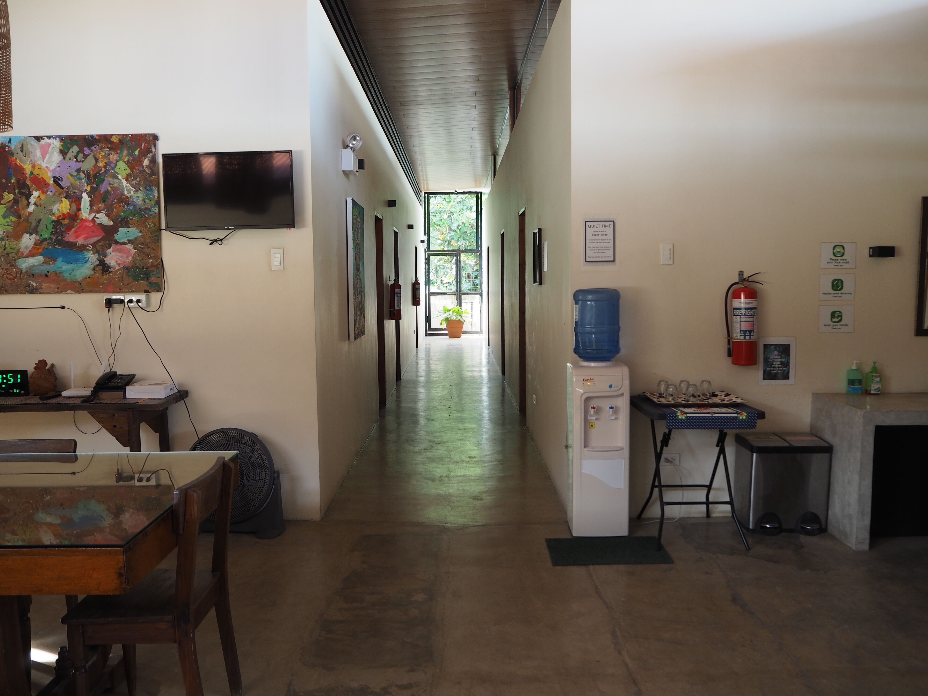 A hallway with a desk, a water cooler, a fire extinguisher, and a sign indicating quiet time.