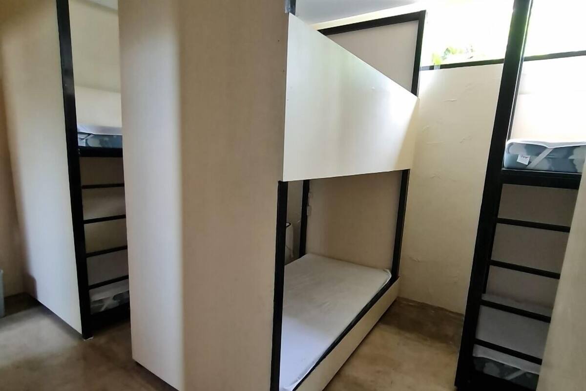 Habitación con literas, una cama individual en la parte inferior y una puerta entreabierta a otra habitación.