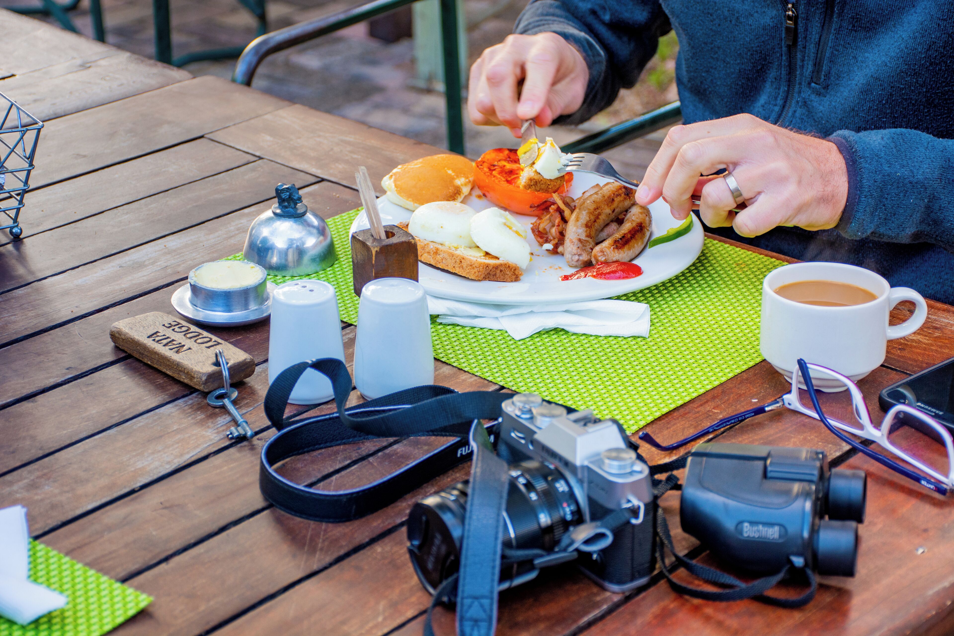 Una mesa de madera con una cámara, un par de gafas y un plato de comida.