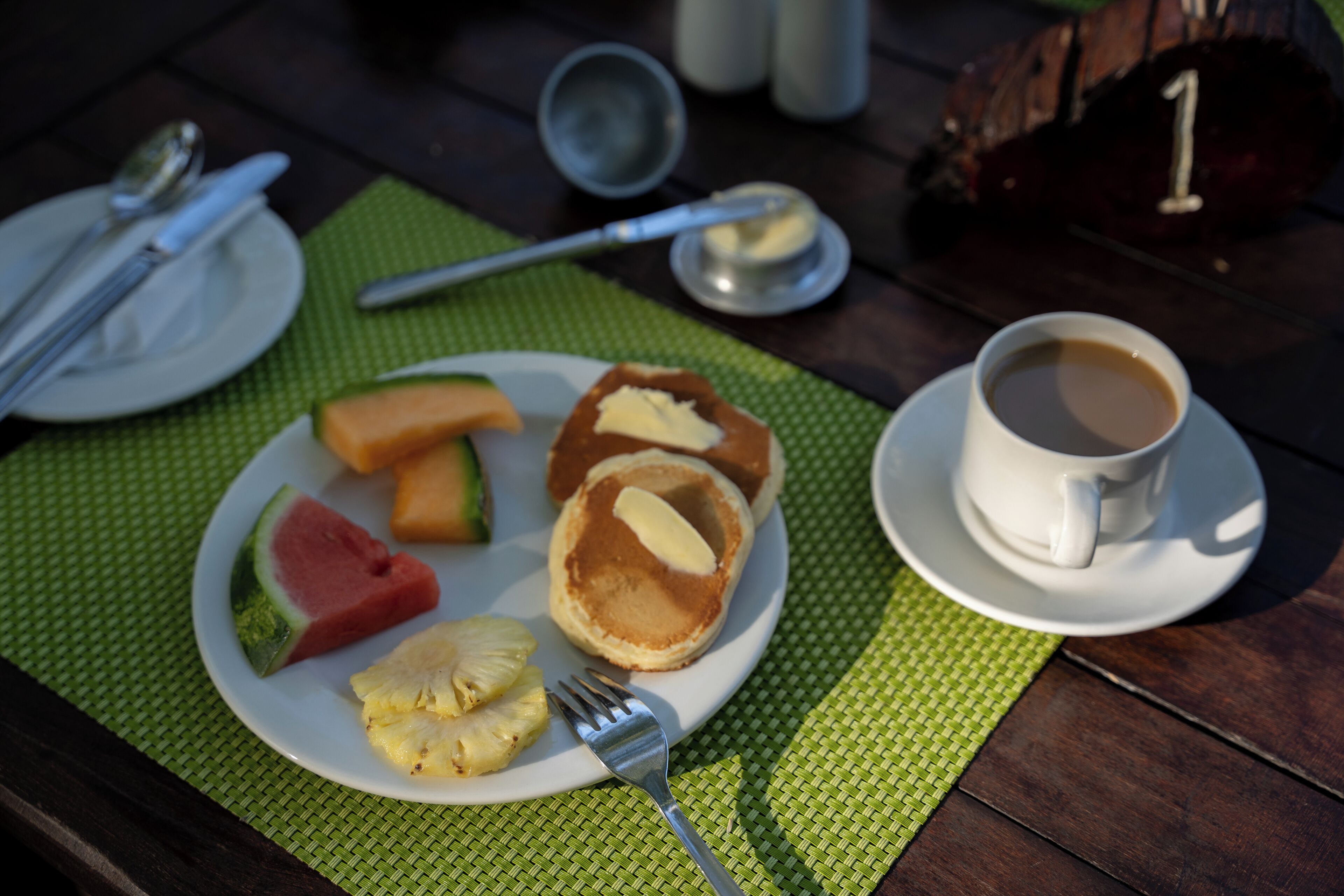 A table with a plate of food, a cup of coffee, and a fork.