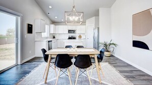 Une cuisine moderne avec des meubles blancs, un îlot central et un luminaire suspendu.