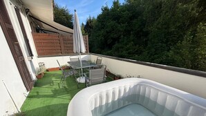 Um pátio externo com hidromassagem, uma mesa com cadeiras e um cercado de madeira.