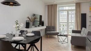 Un salón moderno con comedor, sofá gris y un amplio ventanal con vistas a la ciudad.