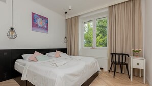 Un dormitorio moderno con cama, escritorio, silla y ventana con cortinas.