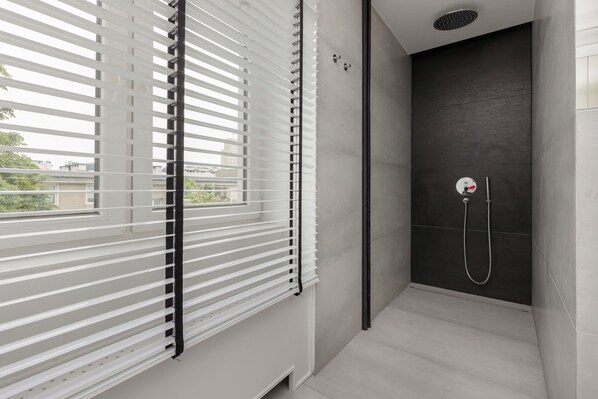Un baño moderno con ducha, una ventana con persianas y vistas al exterior.