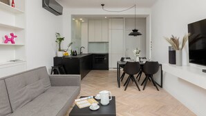 Una sala moderna con un sofá gris, una mesa de centro negra con una bandeja, y un comedor con una mesa y sillas negras.
