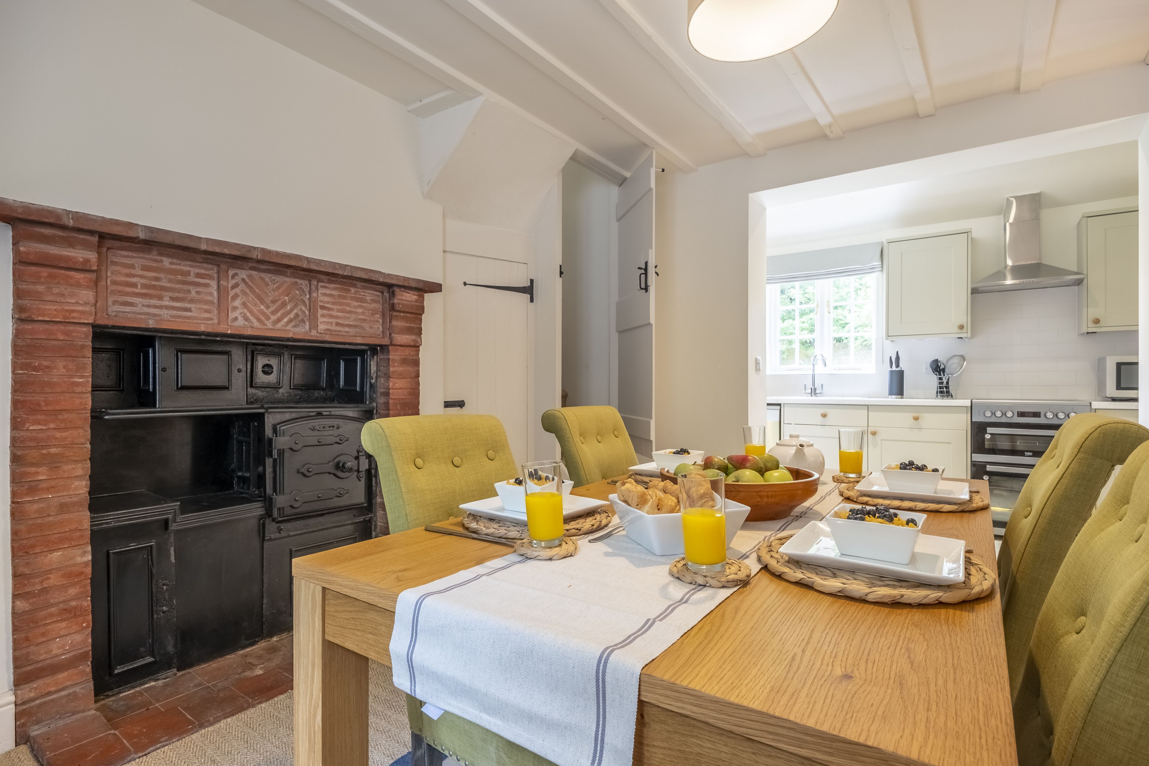 A dining area with a wooden table set for breakfast, including plates, bowls, and glasses of orange juice.