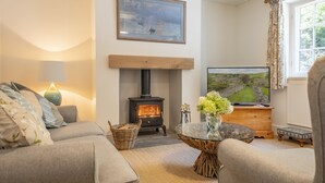 A cozy living room with a fireplace, comfortable seating, and a television. - The Vicarage Cottage -  an idyllic cottage in Great Limber sleeping 4 guests (Great Limber)