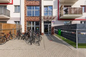 Un edificio con fachada de ladrillo, entrada protegida por una reja y bicicletas estacionadas afuera.