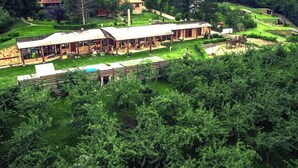 A large, rustic building with multiple rooms and a covered outdoor area, surrounded by lush greenery and hills. - Zdravkovac Country Club (Topola)
