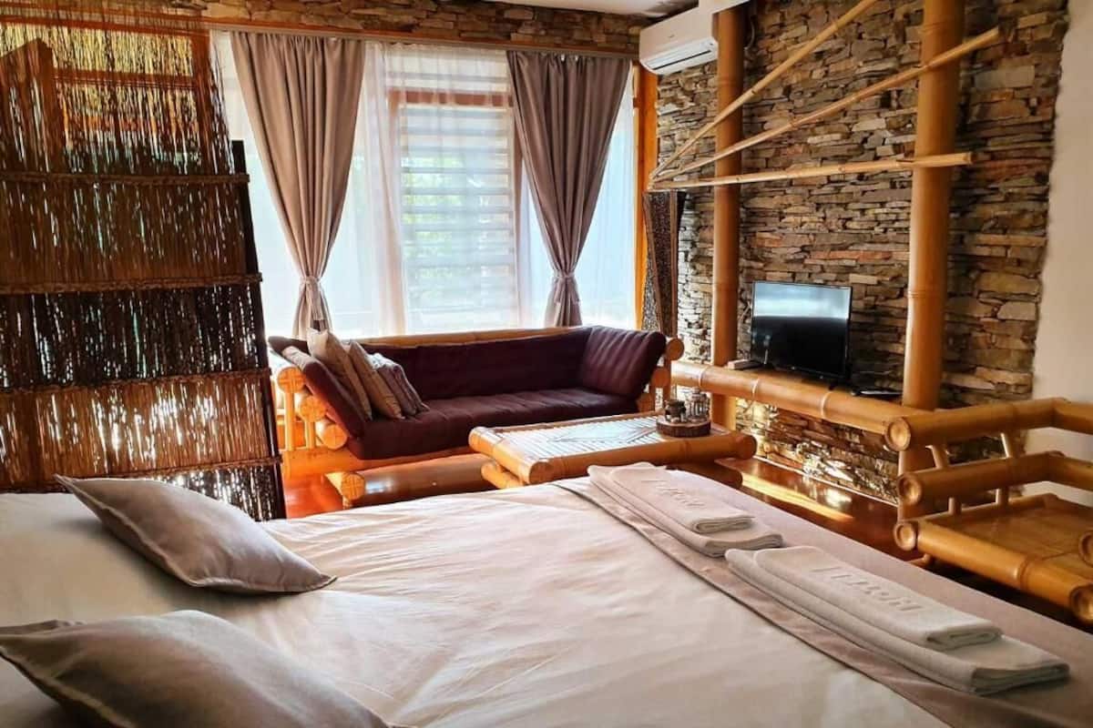 Una habitación de hotel con cama, sofá, televisión y pared de piedra.
