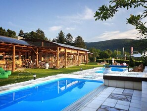 A pool area with a wooden deck and a covered seating area.