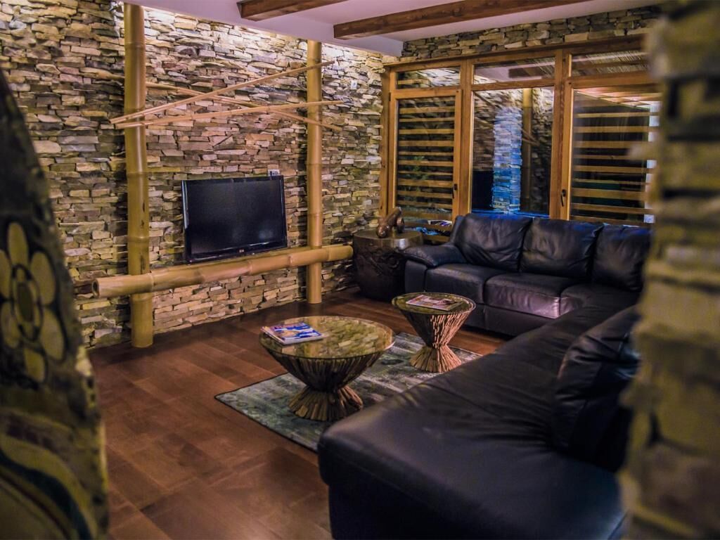 A cozy living room with a stone wall, a leather sofa, and a television.