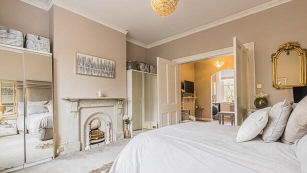A bedroom with a large bed, a fireplace, a mirror, and a wardrobe. - Ground Floor 1 Bedroom Flat - Windsor By Tempstay (Berkshire)