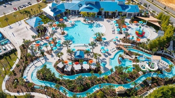 Eine Vogelperspektive eines Resorts mit mehreren Swimmingpools, Liegestühlen und einer Rutsche.