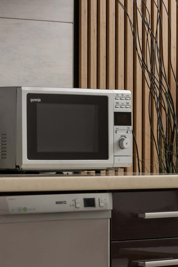 A microwave oven with a digital display and control buttons on a kitchen counter.