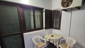 Une petite pièce dotée d’une porte-fenêtre coulissante, d’une table avec quatre chaises, d’une nappe et d’un appareil de climatisation.