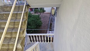 Un escalier avec des balustres blanches et une main courante, menant à un palier doté d’une rambarde blanche.