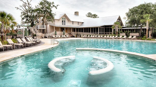 A swimming pool with lounge chairs and a building with a covered patio area.