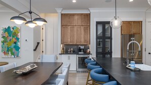 A modern kitchen with a dark countertop, bar stools, and a large island.