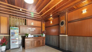 Un espace d’accueil avec un comptoir de réception en bois, un réfrigérateur et une horloge murale.