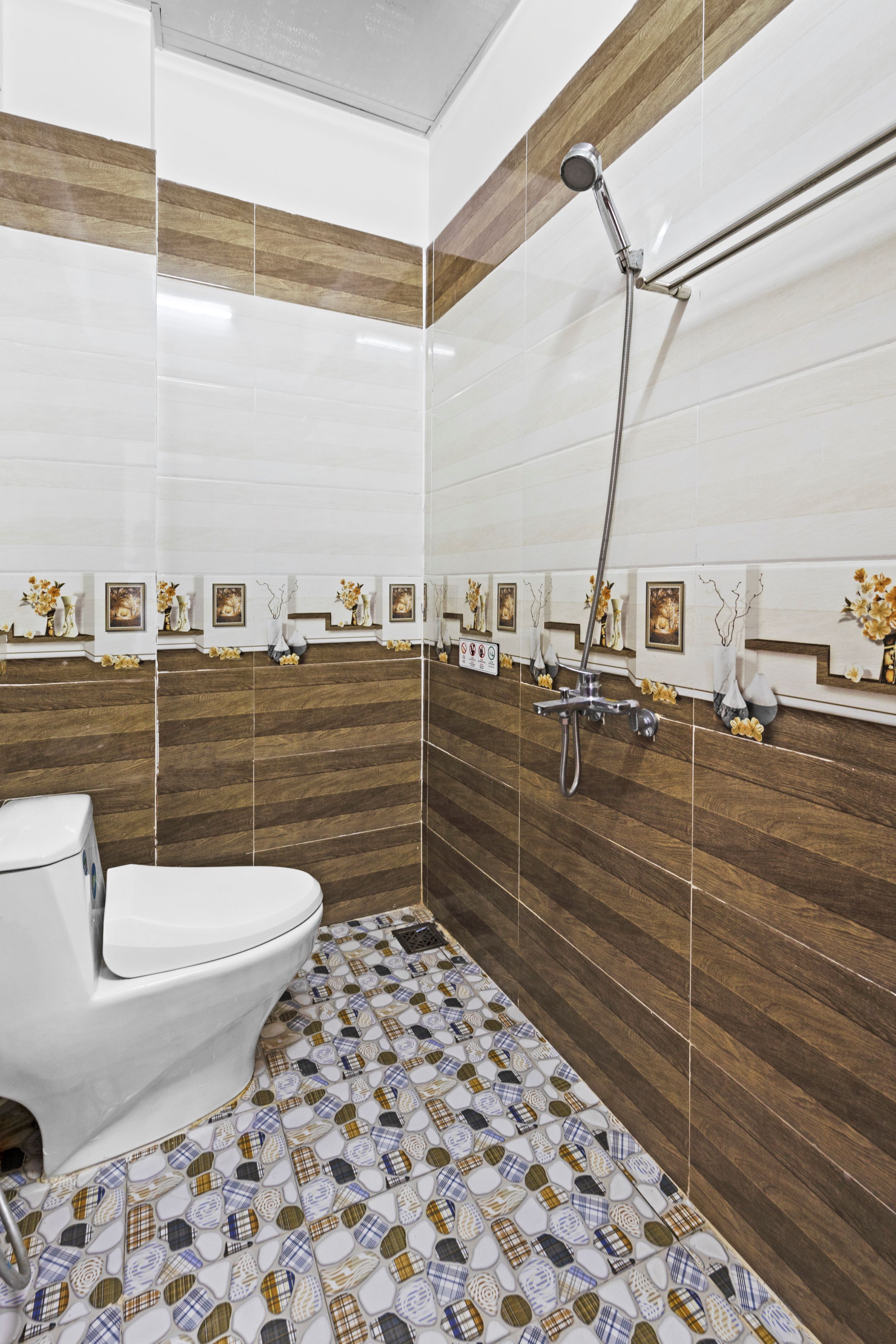A modern bathroom with a white toilet, a shower with a chrome head, and patterned tiles on the floor and walls.
