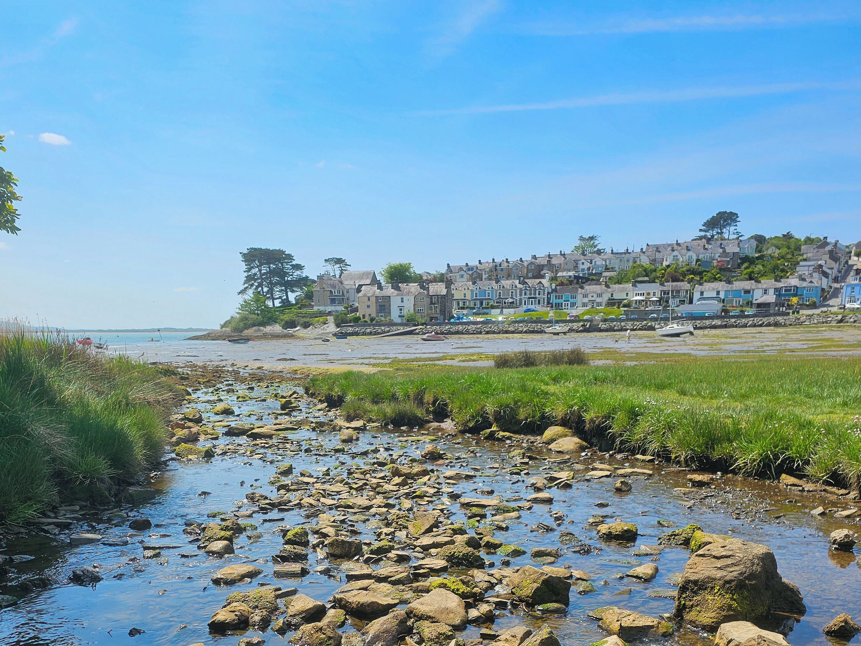 A coastal village with a rocky shoreline, a clear blue sky, and traditional houses.