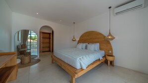 A bedroom with a wooden bed, bedside tables, a hanging light fixture, and a large mirror. - Villa Eliad - 3 Bedroom Villa in Berawa (Canggu)