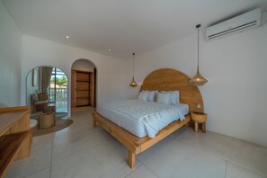 Une chambre à coucher avec un lit en bois, des tables de chevet, un luminaire suspendu et un grand miroir.