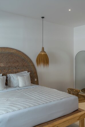 A modern bedroom with a large bed, a hanging light fixture, and a mirror.