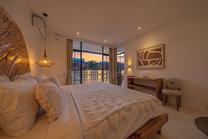 Un dormitorio con una cama grande, un escritorio, una silla y vistas a la ciudad.