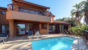A two-story building with a swimming pool, a balcony, and a patio area with chairs and a table. - San Lameer Villa 14323 (Southbroom)