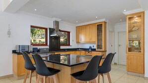 A modern kitchen with a central island, wooden cabinets, and a large window. - San Lameer Villa 14323 (Southbroom)