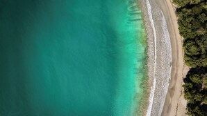 An aerial view of a beach with clear turquoise waters and a sandy shoreline. - Six Senses La Sagesse (St. David)