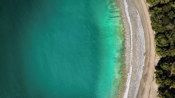 An aerial view of a beach with clear turquoise waters and a sandy shoreline. - Six Senses La Sagesse (St. David)