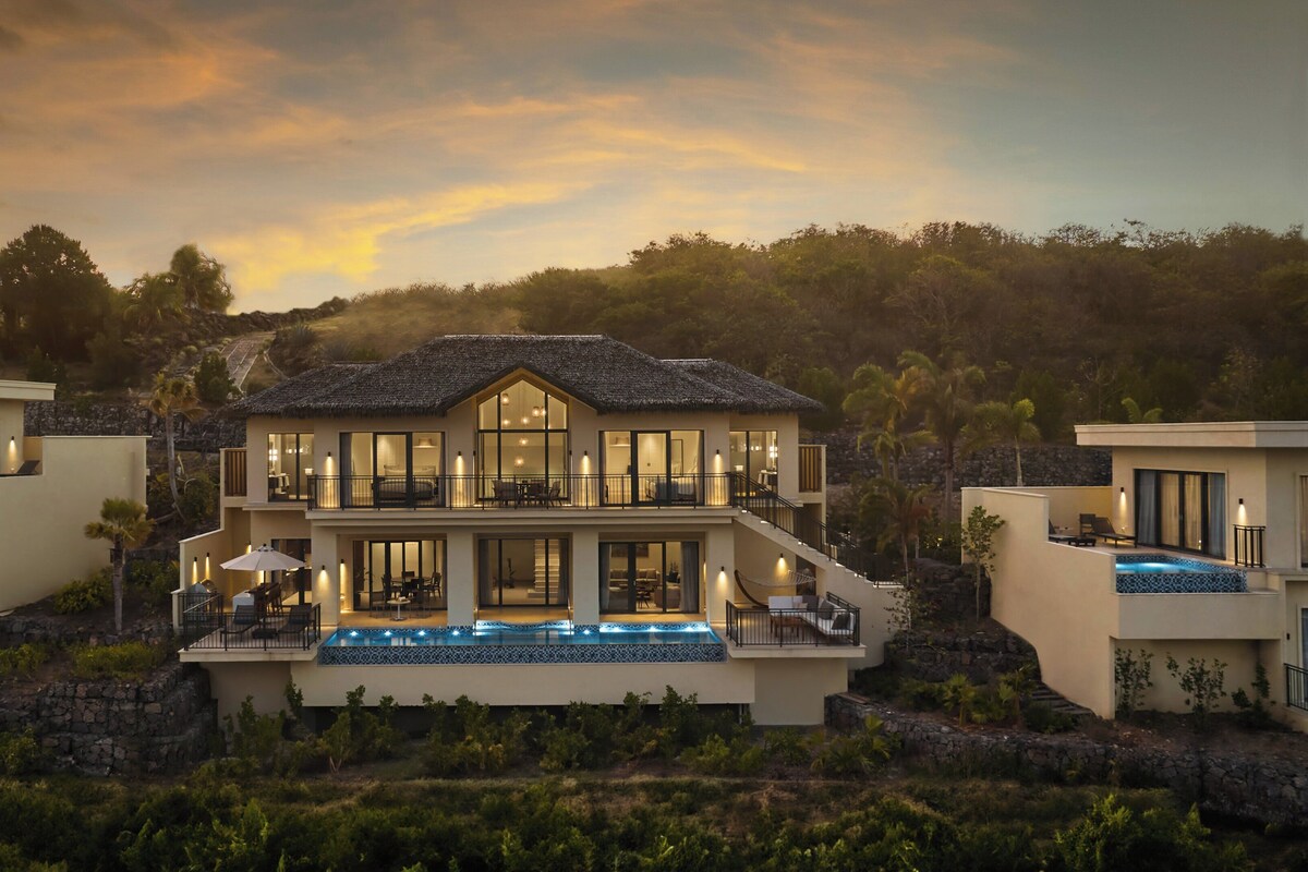 A multi-story house with a large balcony, a swimming pool, and a view of the surrounding landscape.