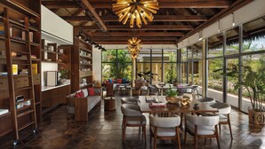 A spacious living area with a large dining table, comfortable seating, and a view of lush greenery outside. - Six Senses La Sagesse (St. David)