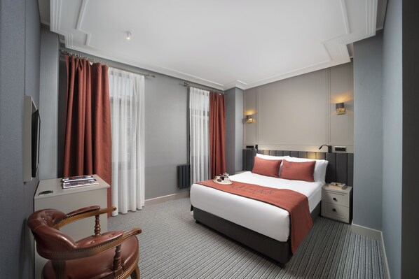 A hotel room with a bed, bedside tables, a desk with a chair, and curtains. -  Union Hotel Plat Inn (Istanbul)