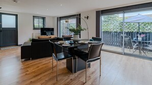 Un área de comedor moderna con una mesa negra, sillas y una planta en maceta.