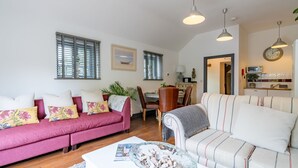 Ein Wohnzimmer mit einem roten Sofa, einem gestreiften Sofa, einem Esstisch und einer Küchenzeile inklusive Mikrowelle.